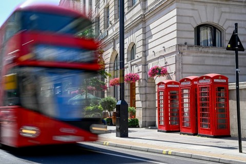 Three traditional telephone boxes and red double-decker bus in Langham Place in front of The