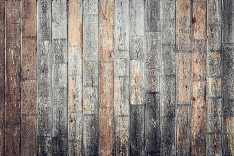 A textured wooden wall with varying shades of brown and gray. The planks are arranged horizontally,