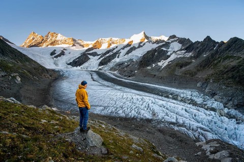 Young man in front of impressive high-alpine landscape, Finsteraarhorn and Agassizhorn mountain