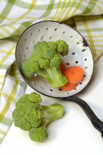 Broccoli in sieve trowel and carrot slices, Brassica oleracea var. italica