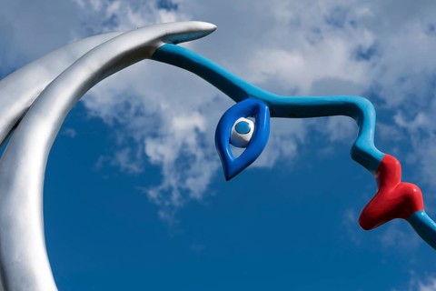 Face against blue sky with clouds, part of a sculptureGiardino dei Tarocchi or Garden of Tarot, by