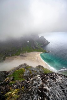 View from Helvetestinden summit, Bunesstranden sandy beach and blue sea, dramatic cloudy sky,