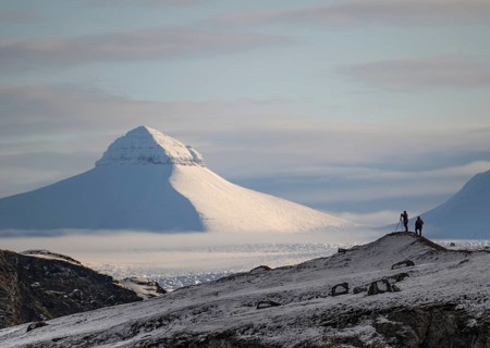 Two people, including a photographer with a stand in front of one of the three mountains Tee