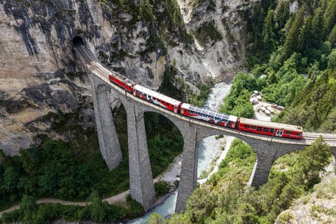 Red train of the Rhaetian railroad line, Bernina Express, passing the Landwasser Viaduct, arch