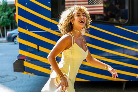 Cheerful young woman with curly blonde hair walking on a sunny day in manhattan, expressing joy and