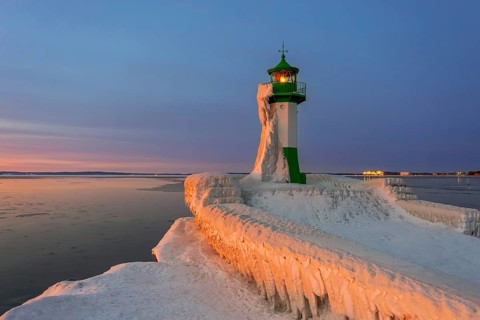 Ice covered Molenfeuer, frozen lighthouse, pier light on mole in Sassnitz harbour at sunrise in