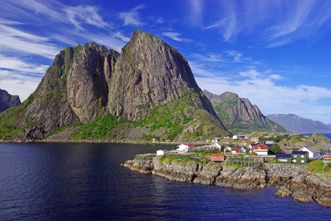 Dramatic mountains and coast with small village under blue sky and clouds, Hamnoey, Lofoten,