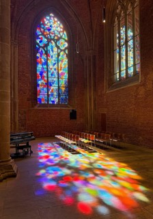 Stained glass window by Alfred Manessier with colorful light spots on the floor in the City Church