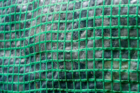 Close-up of a green woven plastic greenhouse fabric