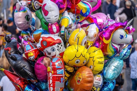 Many colorful motif balloons, filled with gas, float, with many different motifs, some comic