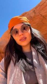 Young woman posing for a selfie during an adventure trip, wearing a bandana and sunglasses,
