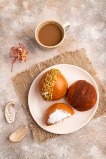 Maritozzo traditional Italian bun dessert, cup of coffee, on brown concrete background with linen