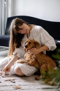 Woman in a white dress with a dog cocker spaniel, surrounded by puzzle pieces, in relaxed setting