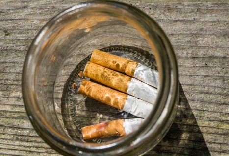 Cigarette butts in a glass ashtray