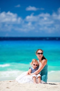 A young woman sits on the beach and holds her daughter in her arms, Seychelles, La Digue, Indian