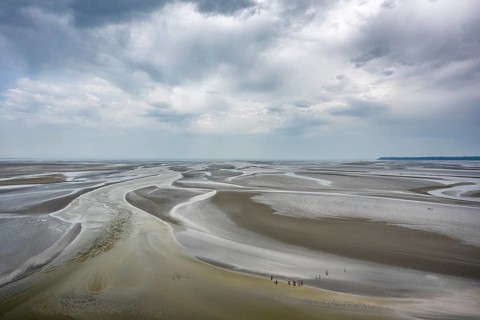 View from the rocky island, monastery island of Le Mont Saint Michel onto a wide mudflat landscape