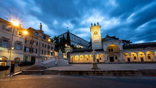 Illuminated main square Piazza della Libertà with Loggia e Tempietto di San Giovanni and clock