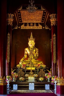 Gilded seated Buddha figure in the public prayer room of the Buddhist temple complex Wat Phra That