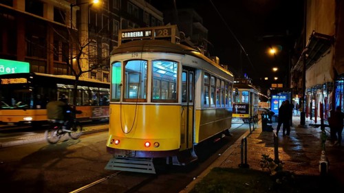 Two trams at night in front of city lights in the lively area of Lisbon, Lisbon, Portugal