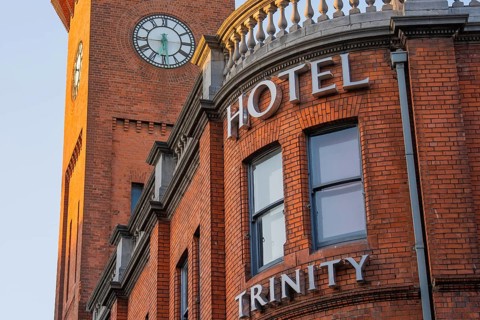 Close-up of brick façade of hotel with clock tower in background, Dublin, Ireland