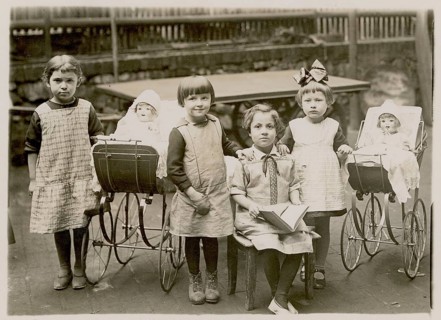Five girls posing with dolls and doll prams in a backyard, schoolbook, children, around 1920