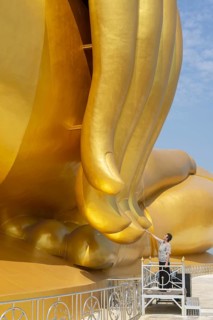 Largest Buddha statue in Thailand (Luang Pho Yai), woman 60-70 touches the fingertips of the statue
