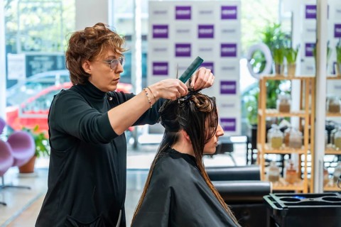 Hairdresser performing a haircut preparation for a female customer in a modern salon, sectioning