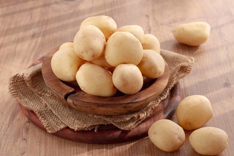 Boiled new potatoes, in a wooden bowl, on a rustic table, natural light, no people