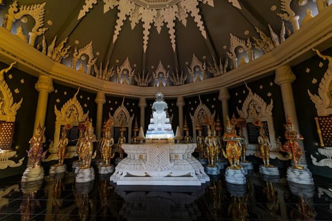 Glass Buddha statue surrounded by figures as heavenly beings and temple guards in the public prayer