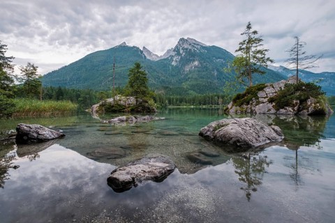 Vertical perspective of the calm waters of Hintersee lake showing rocks under the surface and the