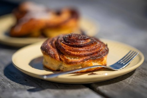 Cinnamon roll and fork lie on a light yellow plate, Houvig, Ringkøbing Fjord, Denmark