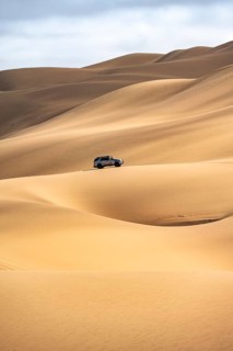 Off-road vehicle between sand dunes, sea of dunes, sandy desert, impressive desert landscape, Namib