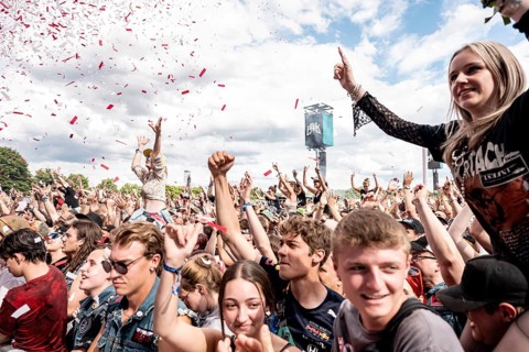Rain of confetti at Finch's performance, festival goers sit on the shoulders of other festival