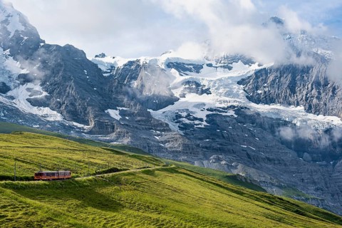 Jungfrau Railway to Jungfraujoch runs through green meadows, above the Kleine Scheidegg stop, rack