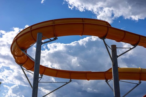 Bright sunlight shines over a fun water slide in a hotel water park in Turkiye. Families and