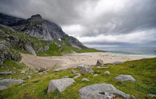 Bunesstranden sandy beach between rocky mountain peaks and dramatic clouds, Lofoten, Norway