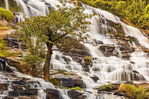 Mae Ya waterfall with cascading flowing water surrounded by lush tropical vegetation, near Doi