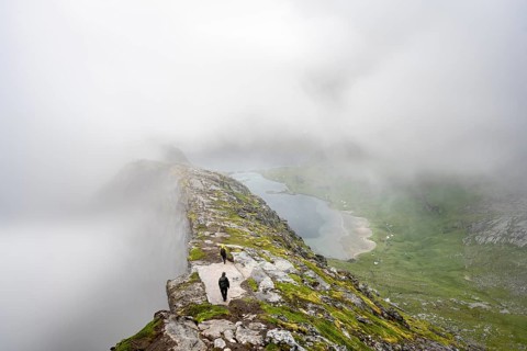 Hikers on the summit of Helvetestinden, cloudy mountain landscape with summit ridge, Lofoten,