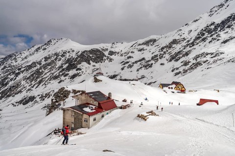 Skiers and mountain huts on snowy Lake Balea in the Fagaras Mountains, South Carpathians,
