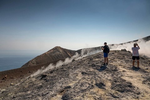 Tourists stand at the crater rim and photograph rising sulfur clouds, Vulcano, Aeolian or Lipari