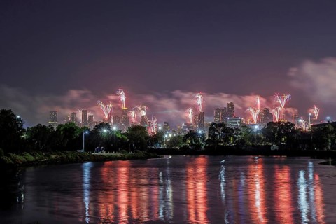 City skyline with fireworks lighting up the night sky, reflections on the river, Fireworks from the