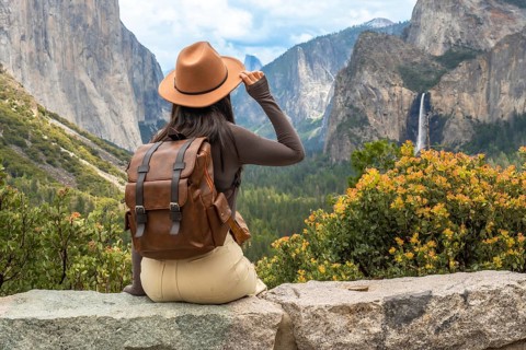 Hiker sitting on a rock ledge, admiring the vast natural beauty of yosemite national park, seeing