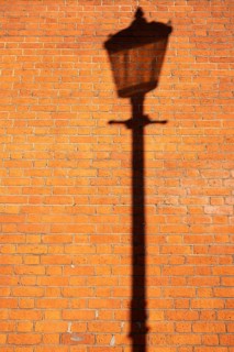 Shadows of a historic street lamp on reddish brown bricks in the evening light, Sloane Square,