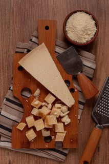 Freshly sliced and grated cheese, parmesan cheese, Gran gusto. Grana padano. on a wooden chopping