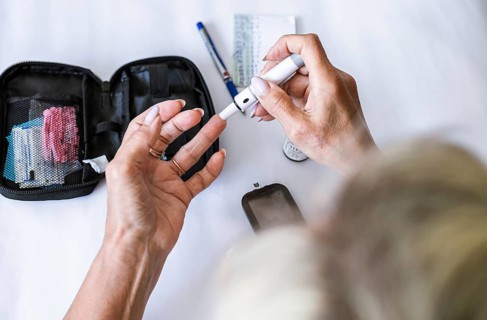 Woman preparing a lancet device for blood glucose testing at home. Diabetes self-care, medical