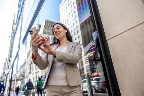 Young businesswoman smiling while interacting with her mobile phone on a vibrant manhattan city