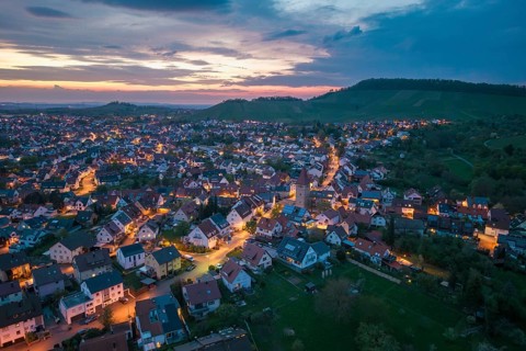 Illuminated urban landscape at dusk with rolling hills and an extensive settlement, Korb im Rems