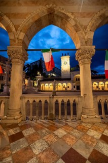 Arcades of the Loggia del Lionello with Italian flags, illuminated main square Piazza della Libertà