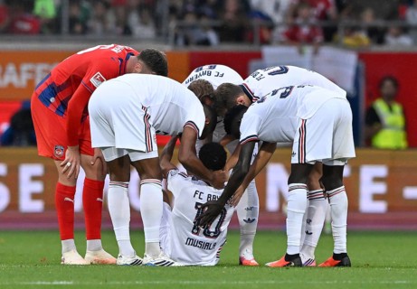 Jamal Musiala of FC Bayern Munich (FCB) (10) collapses on the pitch, teammates come to his aid,