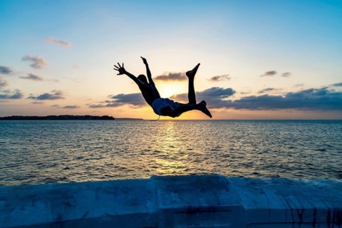 Boy jumping into the sea at sunset in Sao Luis, Maranhao, Sao Luis, Maranhao, Brazil